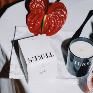 Yafo Suede candle and box from TEKES on a table with a flower